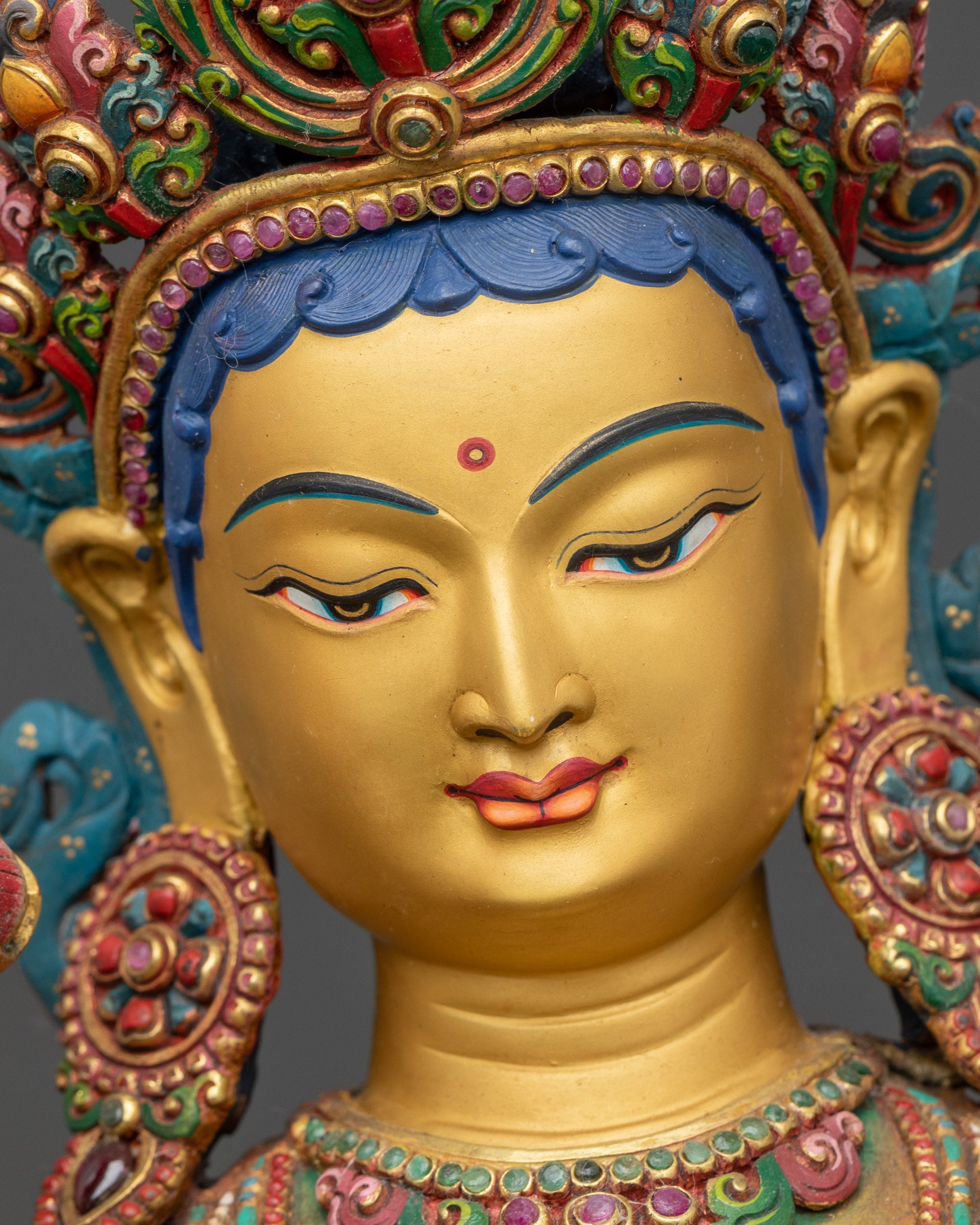 Face detail of Green Tara Meditation statue, gold painted face with serene expression