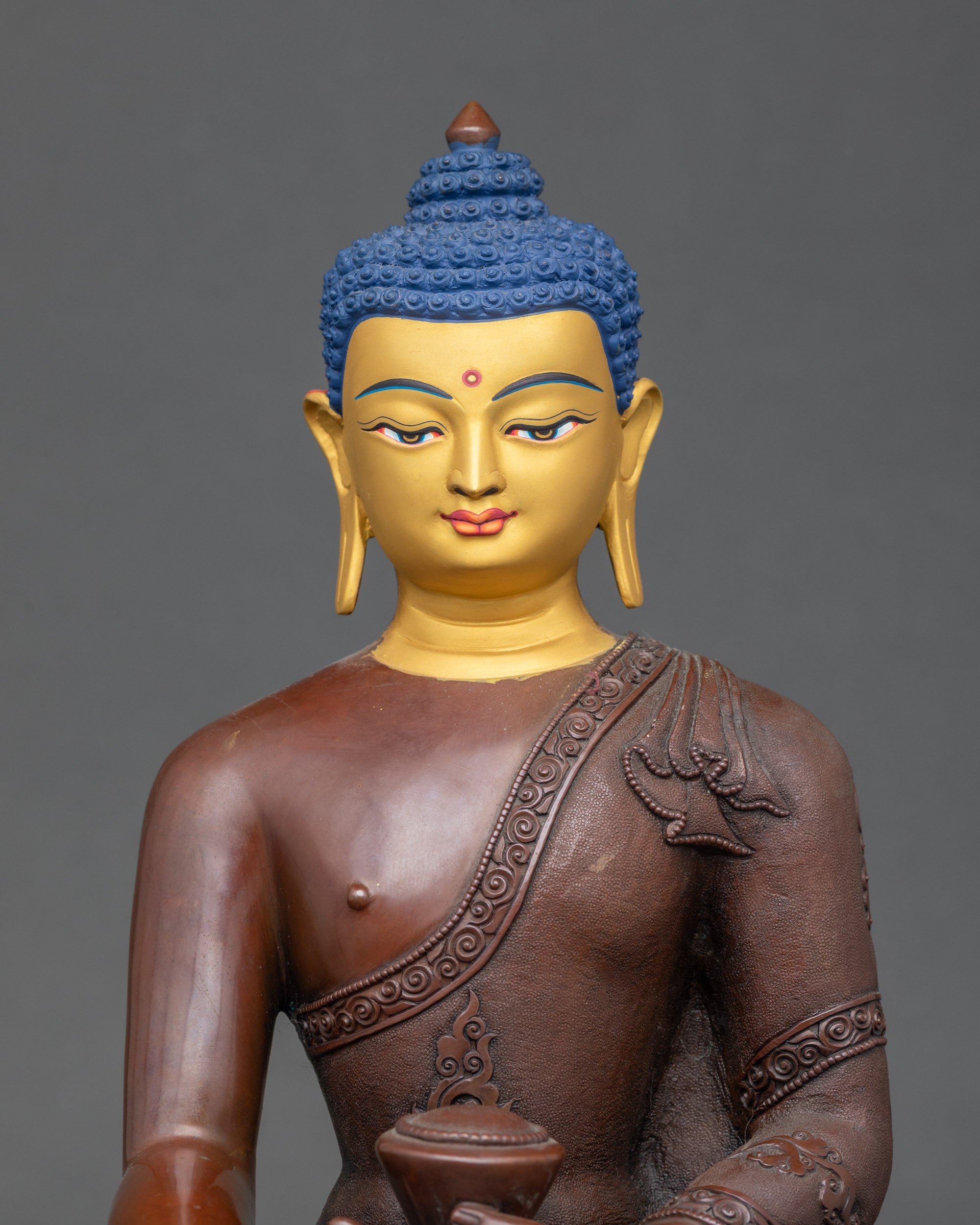 Face detail of Shakyamuni Buddha statue with hand-painted gold expression