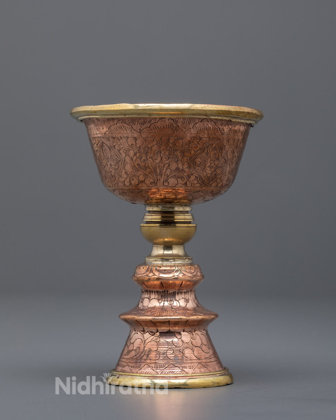 Front angle of hand-carved copper butter lamp with sacred Himalayan motifs