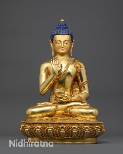 Front view Amoghasiddhi Buddha statue seated on lotus with gold-gilded face and robe