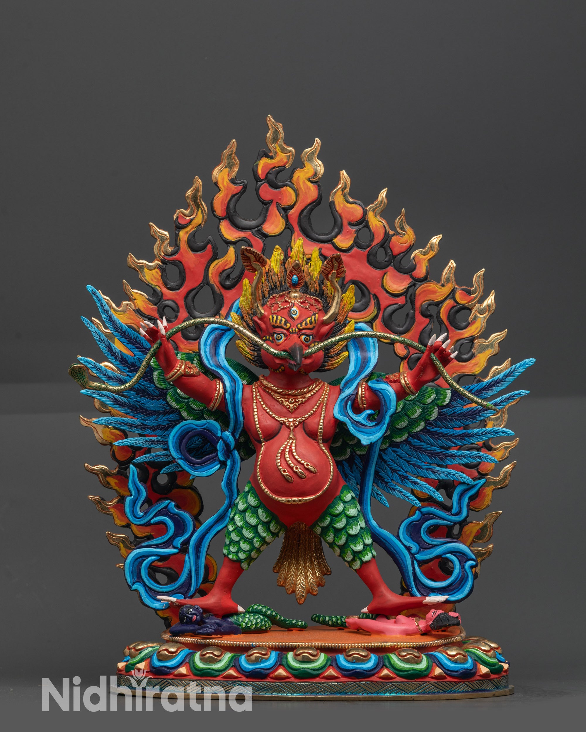 Front view Divine Garuda Sculpture with red body and blue wings on lotus seat
