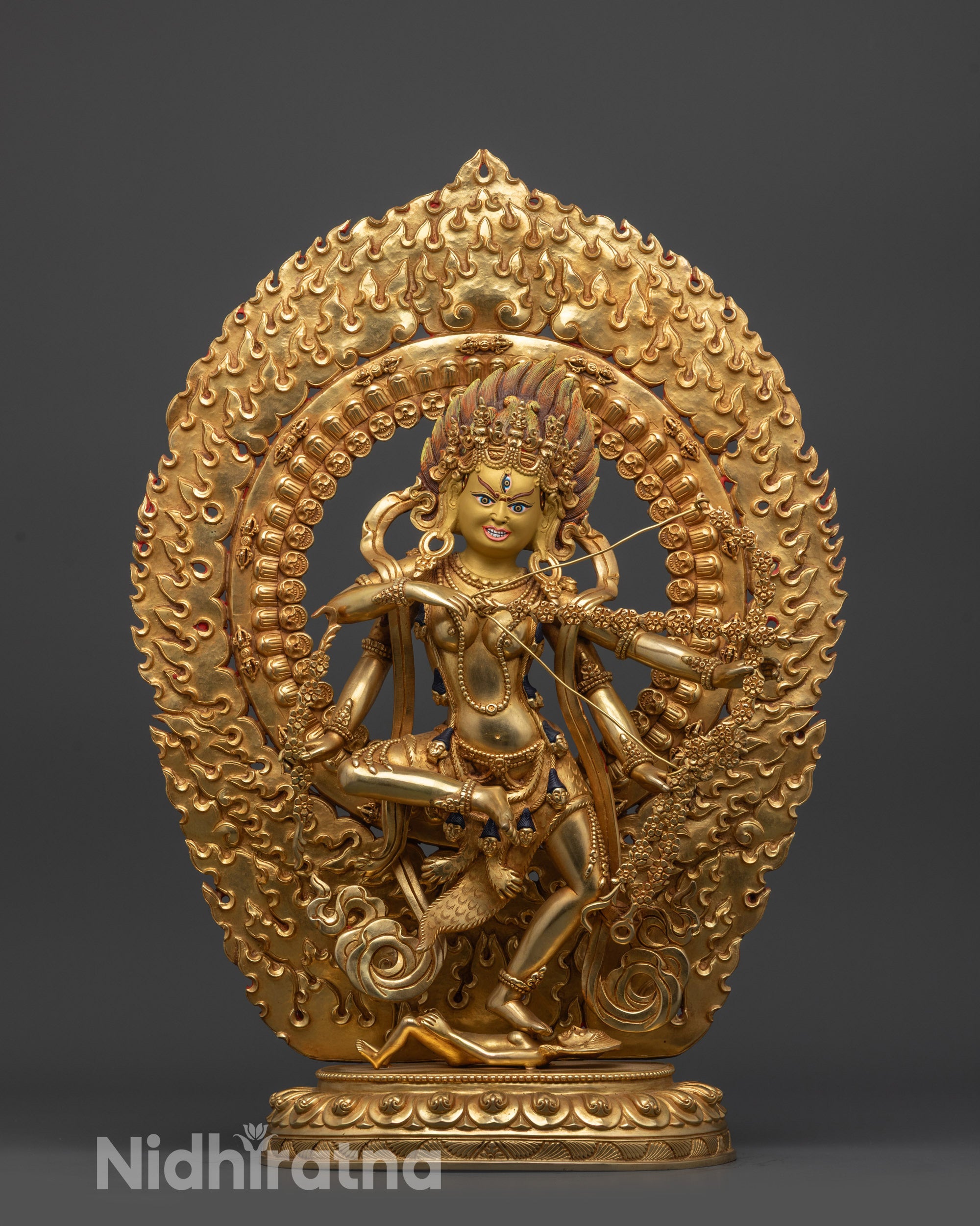 Front view Kurukulla statue with gold-gilded face and fire-gilded body standing on figure

