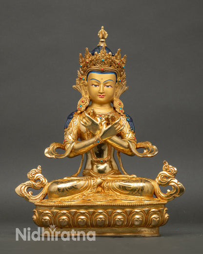 Front view Vajradhara statue with crossed arms holding vajra and bell, gold crown