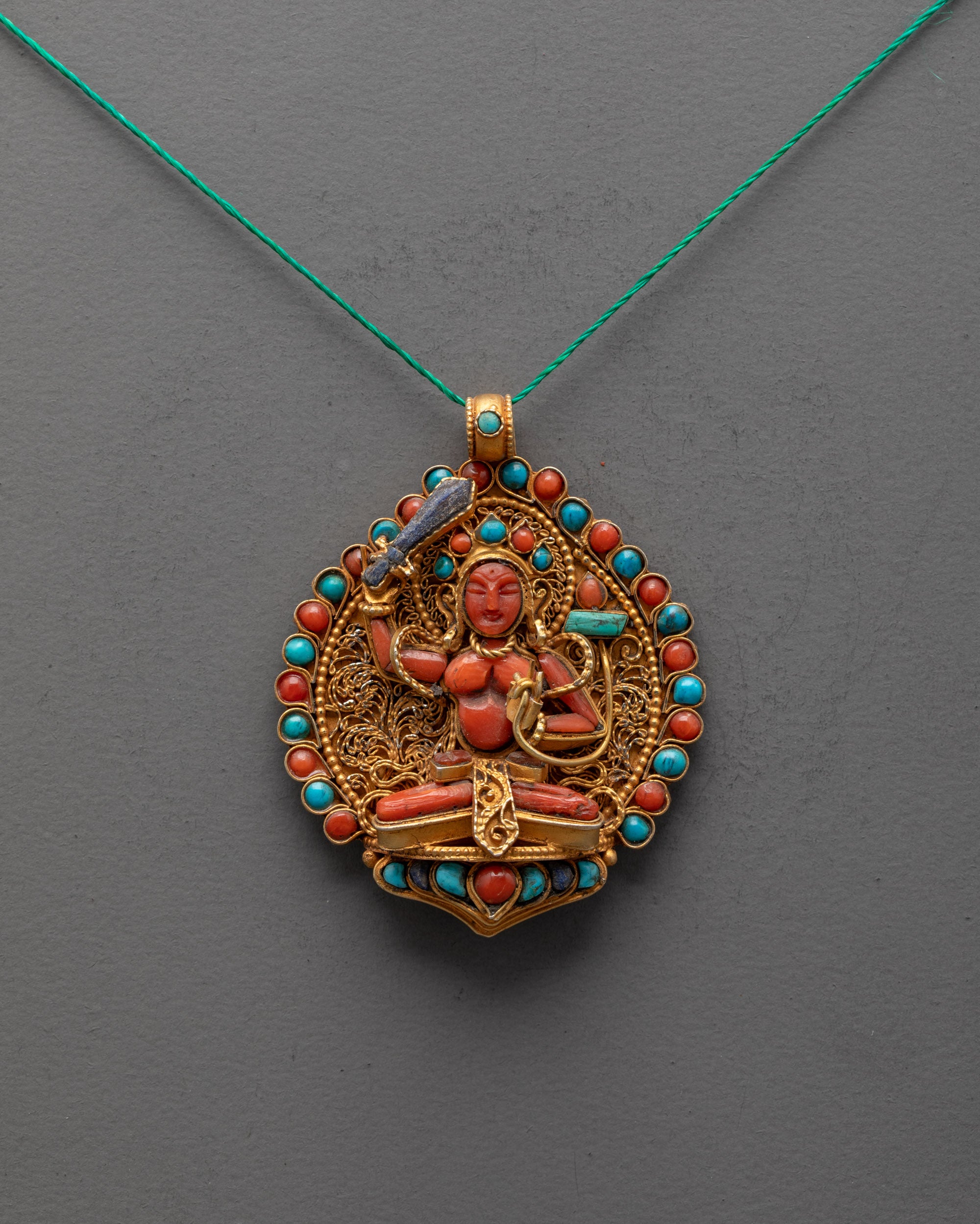 Front view of Coral Manjushri Locket with lapis sword and turquoise book, gold filigree design
