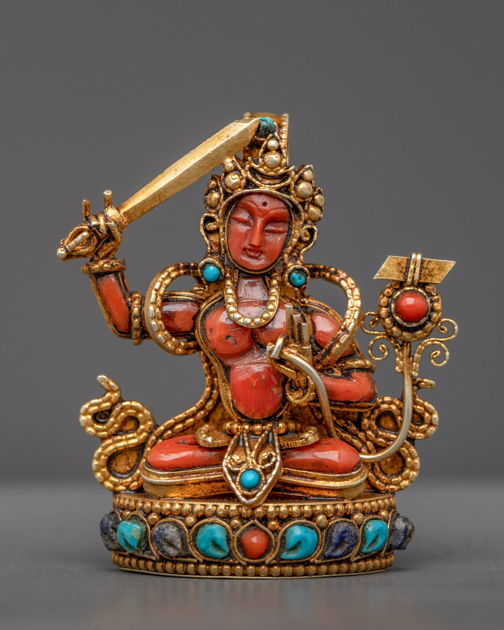 Front view of Coral Manjushri Pendant with gold-gilded sword and detailed filigree design