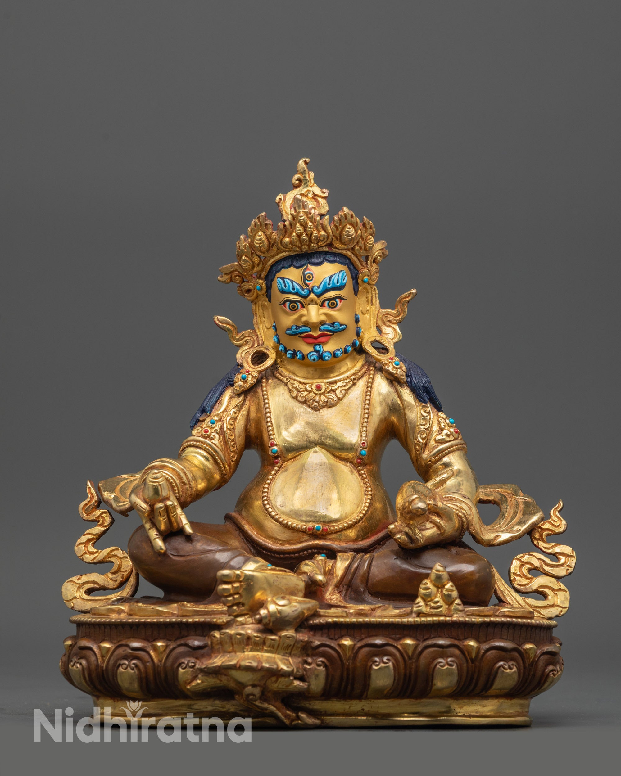 Front view of Dzambhala Statue with gold-gilded face and fire-gilded robes seated on lotus base
