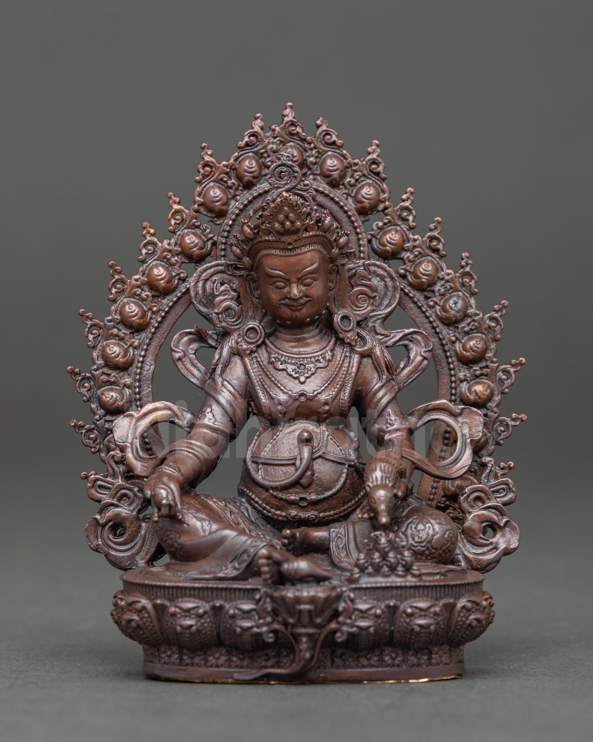 Front view of Dzambhala statue seated on a lotus, holdinga  a mongoose and jewels, chemically oxidized brown finish