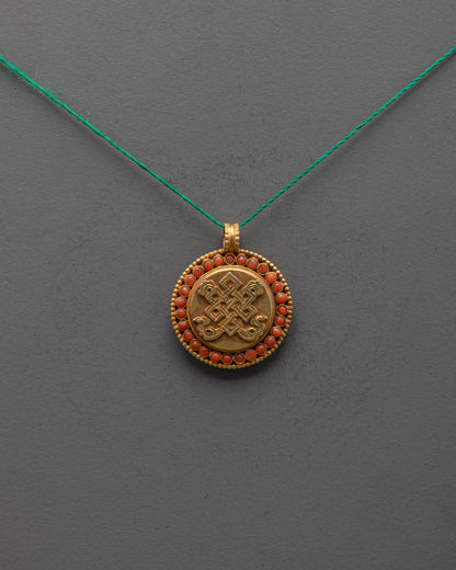 Front view of Endless Knot Locket with coral stones and gold-plated copper finish from Nepal