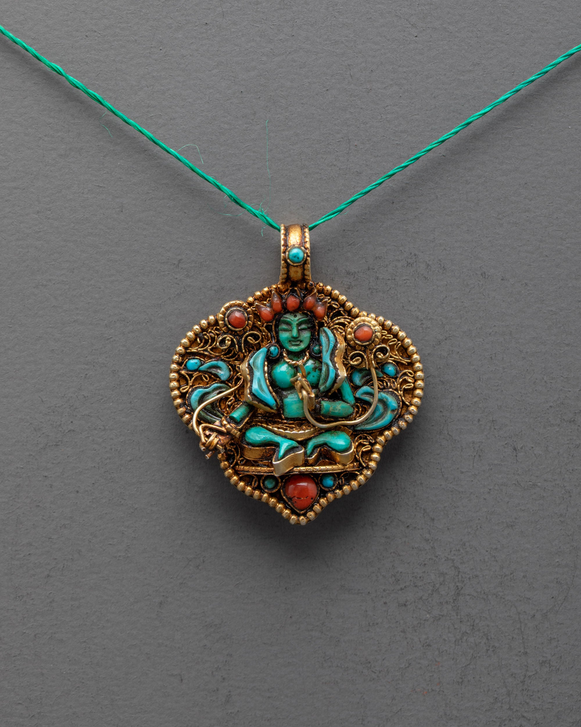 Front view of Green Tara Locket with green crystal deity, turquoise stones, and gold-gilded filigree, handcrafted by artisans in Patan, Nepal.