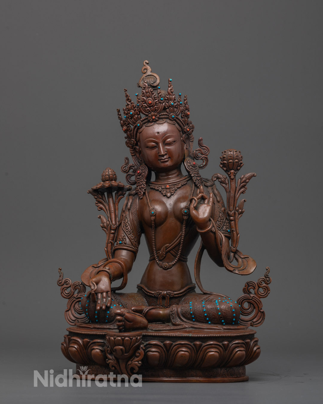 Front view of Green Tara Sculpture seated on a lotus base, hand-carved from oxidized copper
