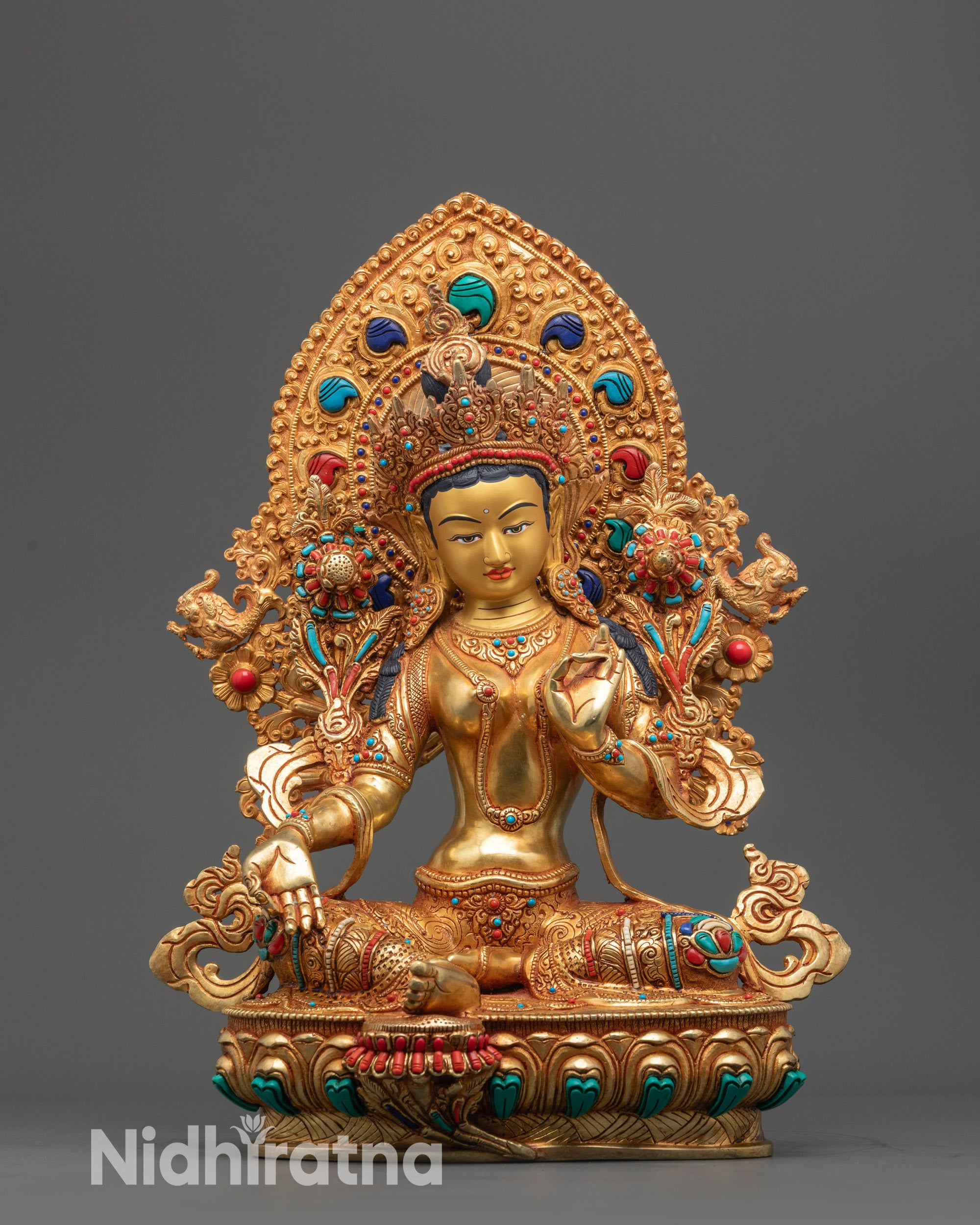 Front view of Green Tara statue with gold-gilded face and utpala flower in hand.