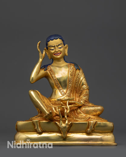 Front view of Milarepa statue on gold fire-gilded base with deer skin-draped pedestal