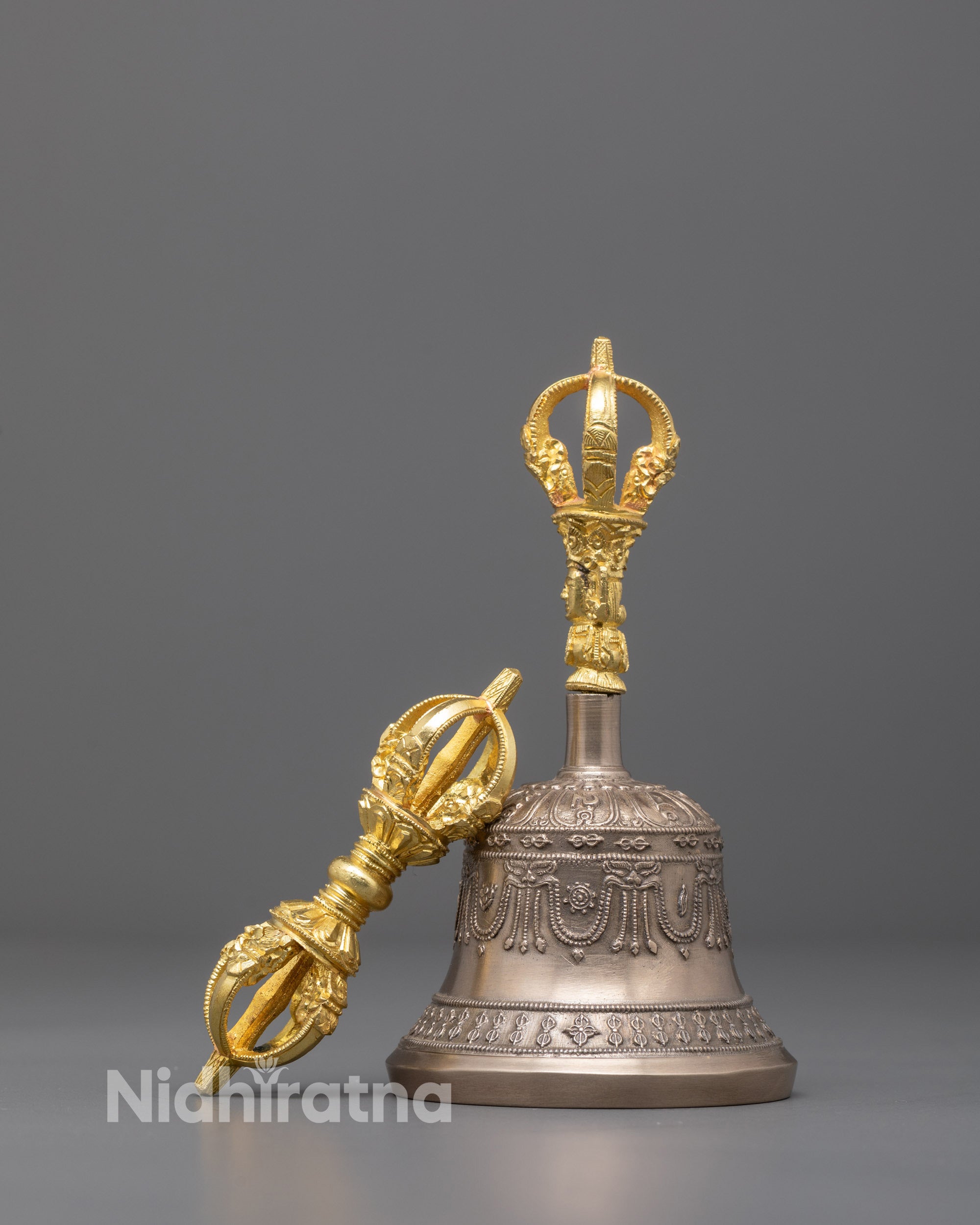 Front‑view of Nepalese handmade copper dorje and bronze prayer bell set showing gold‑plated handle deity and sacred symbol carving