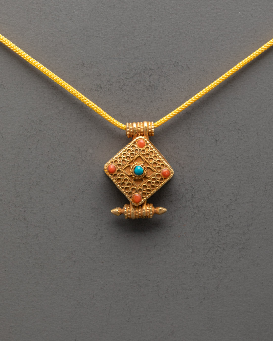 Front view of Religious Tibetan Pendant with gold gilding and vibrant semi-precious stones
