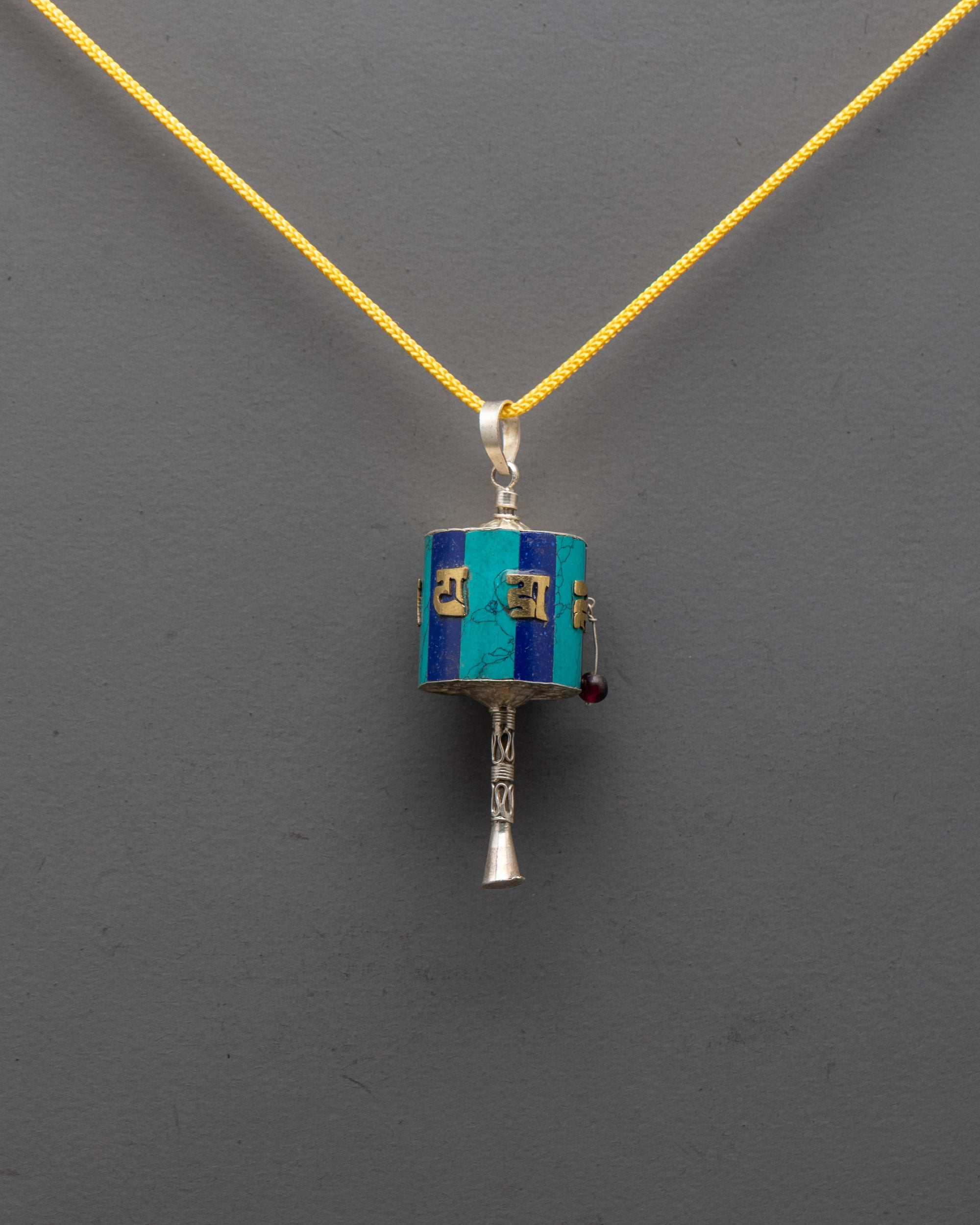 Front view of Tibetan Prayer Wheel Locket with gold-plated mantra on pure silver body
