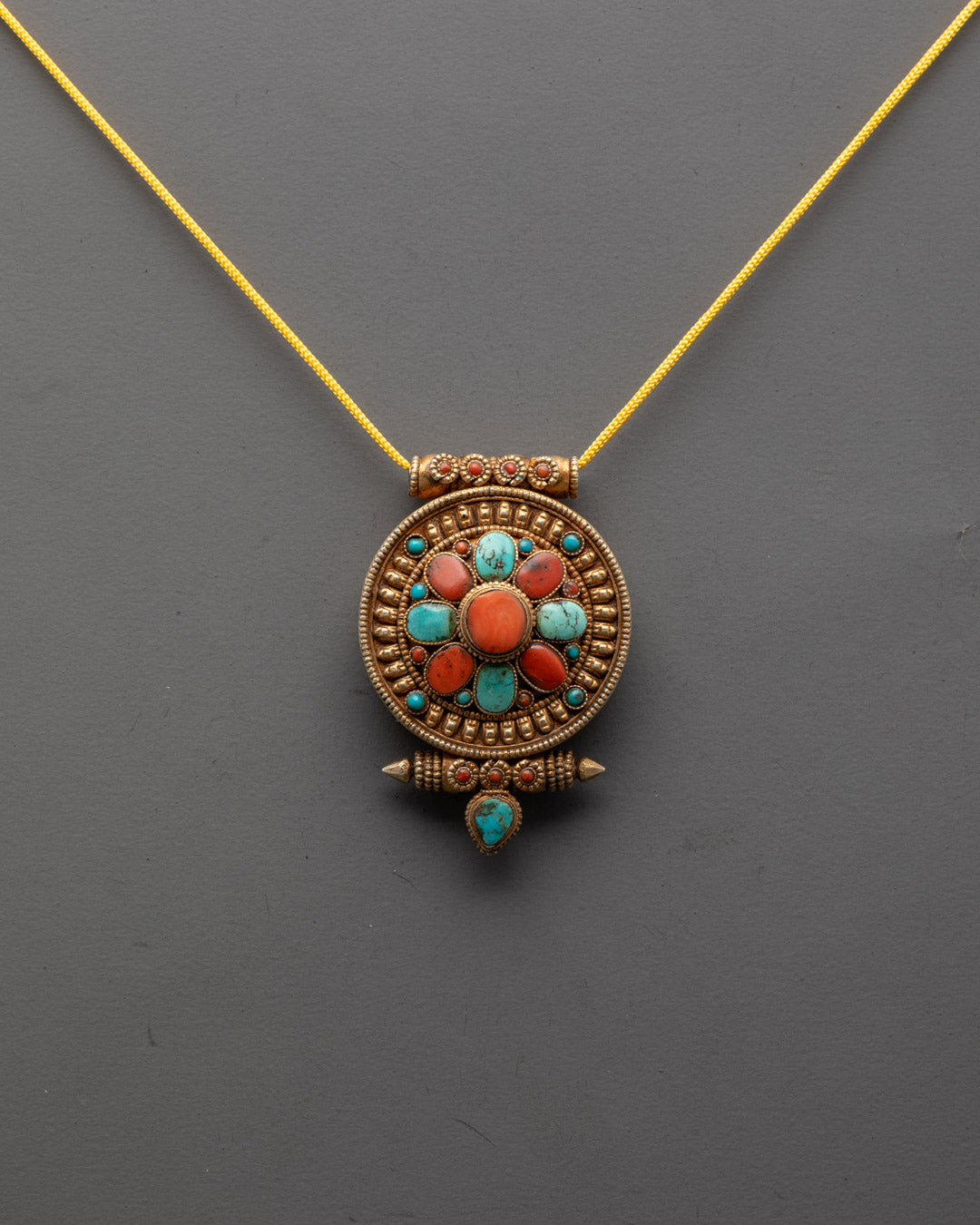 Front view of Tibetan Protection Pendant with gold plating and vibrant turquoise and coral stones

