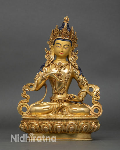 Front view of Vajrasattva statue seated on lotus with vajra and bell, gold fire-gilded
