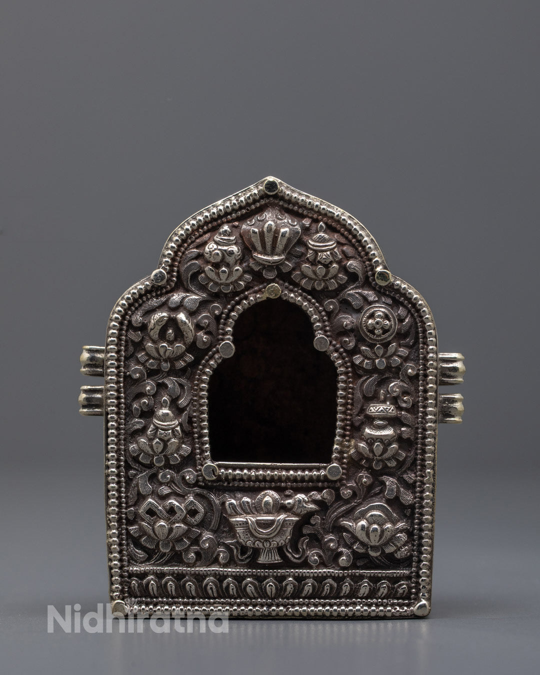 Front view of a hand-carved silver-plated Tibetan Ghau Box with intricate floral 