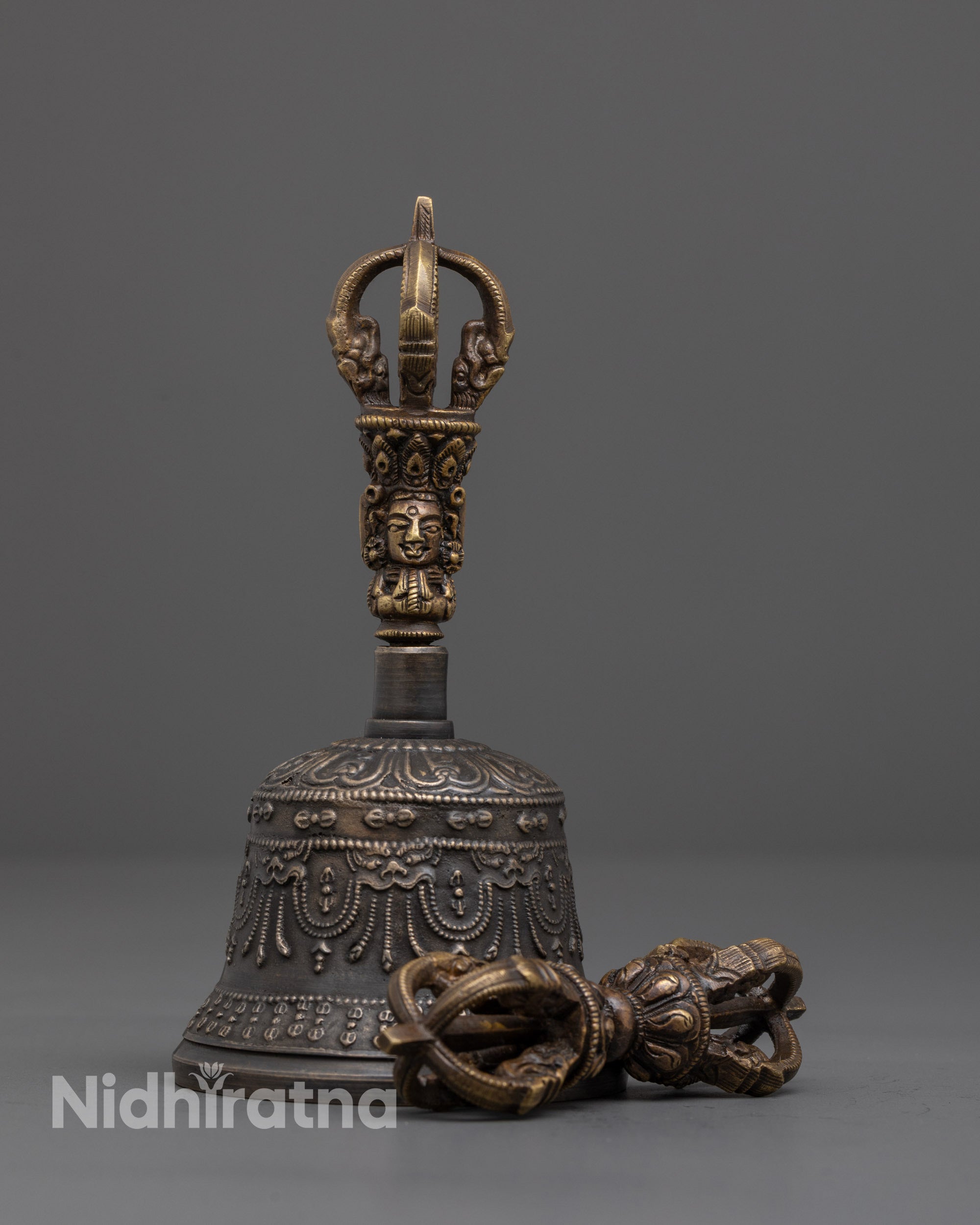 Front view of bronze Vajra and brass-handled bell set with deity carving