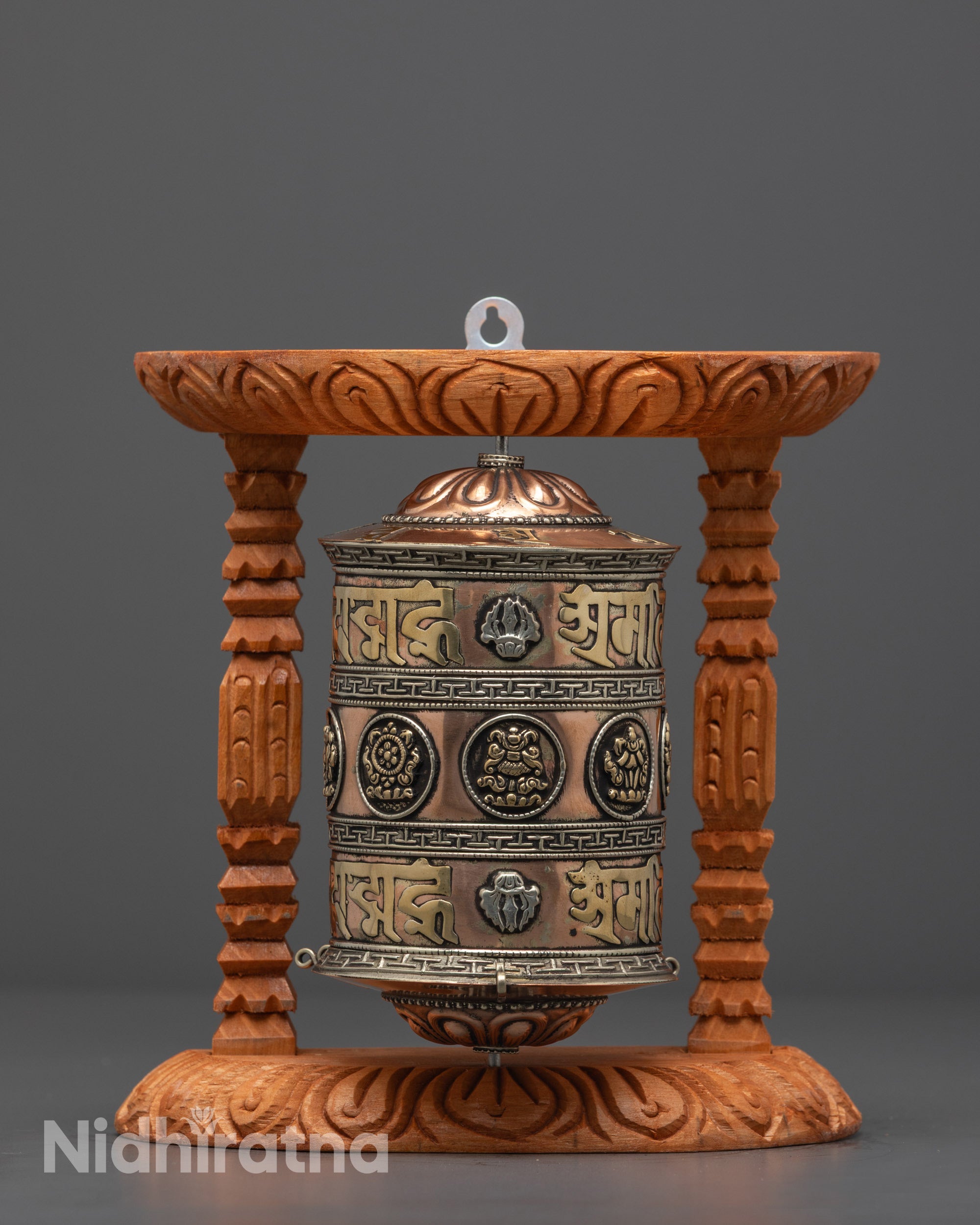 Front view of copper and brass Mantra Prayer Wheel with silver-plated symbols on wood frame