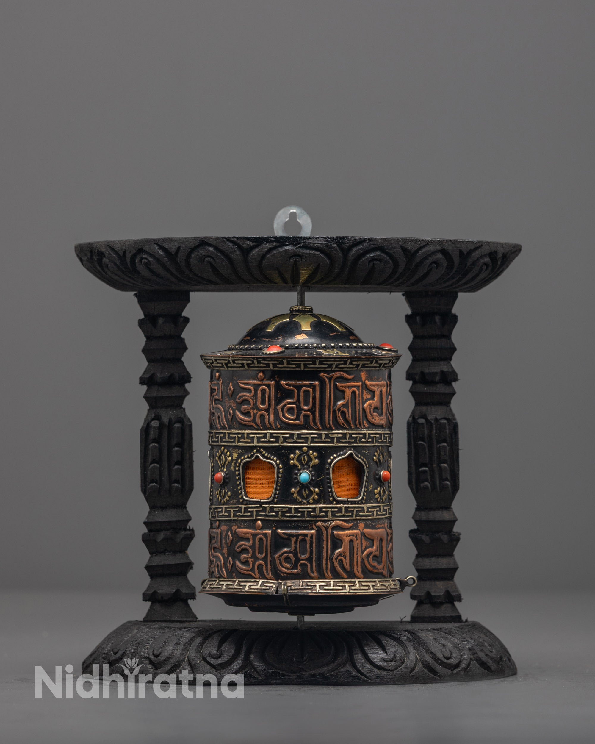 Front view of copper and brass mantra prayer wheel with turquoise and coral stones