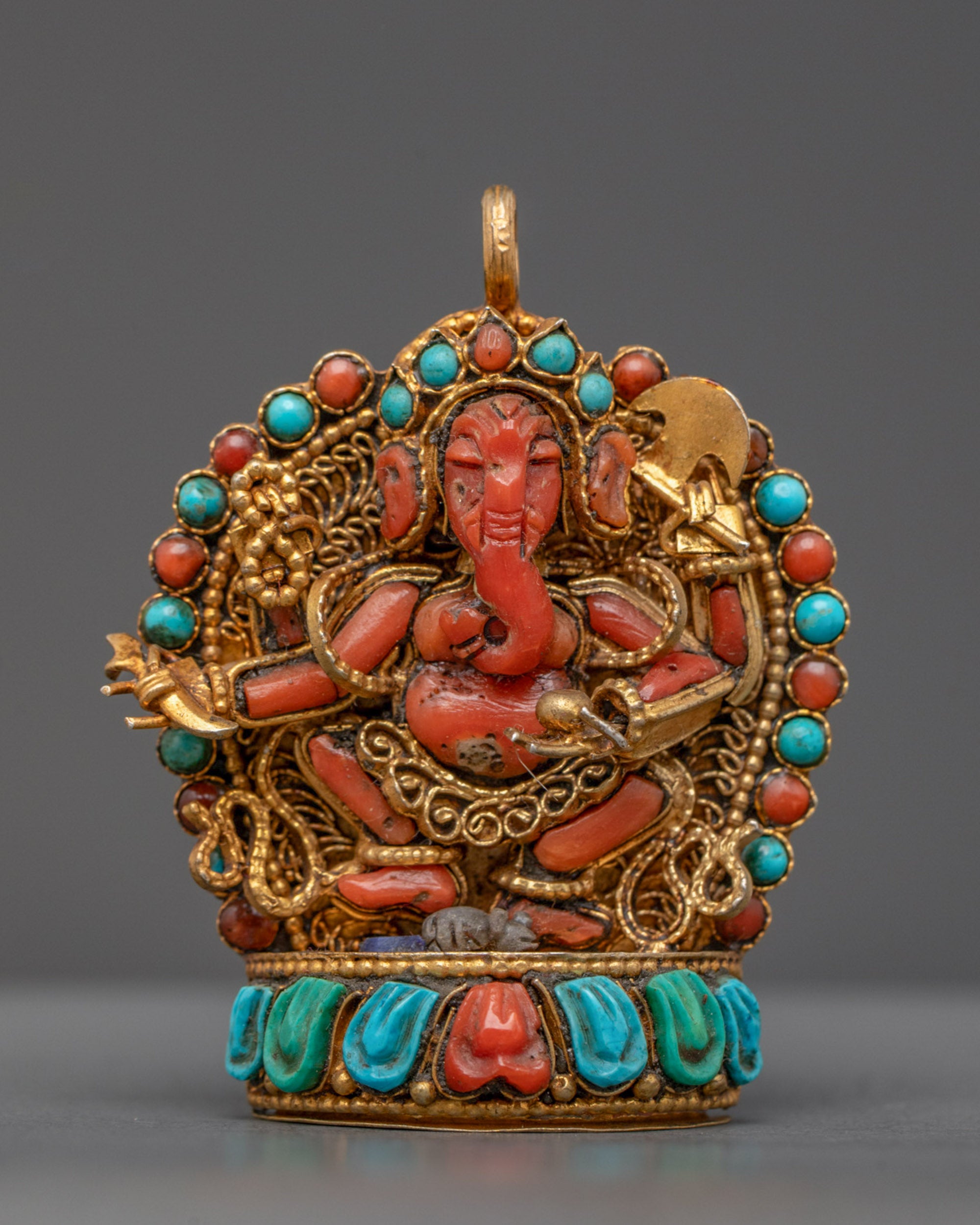 Front view of coral Ganesh locket with gold filigree and semi-precious stones on lotus seat