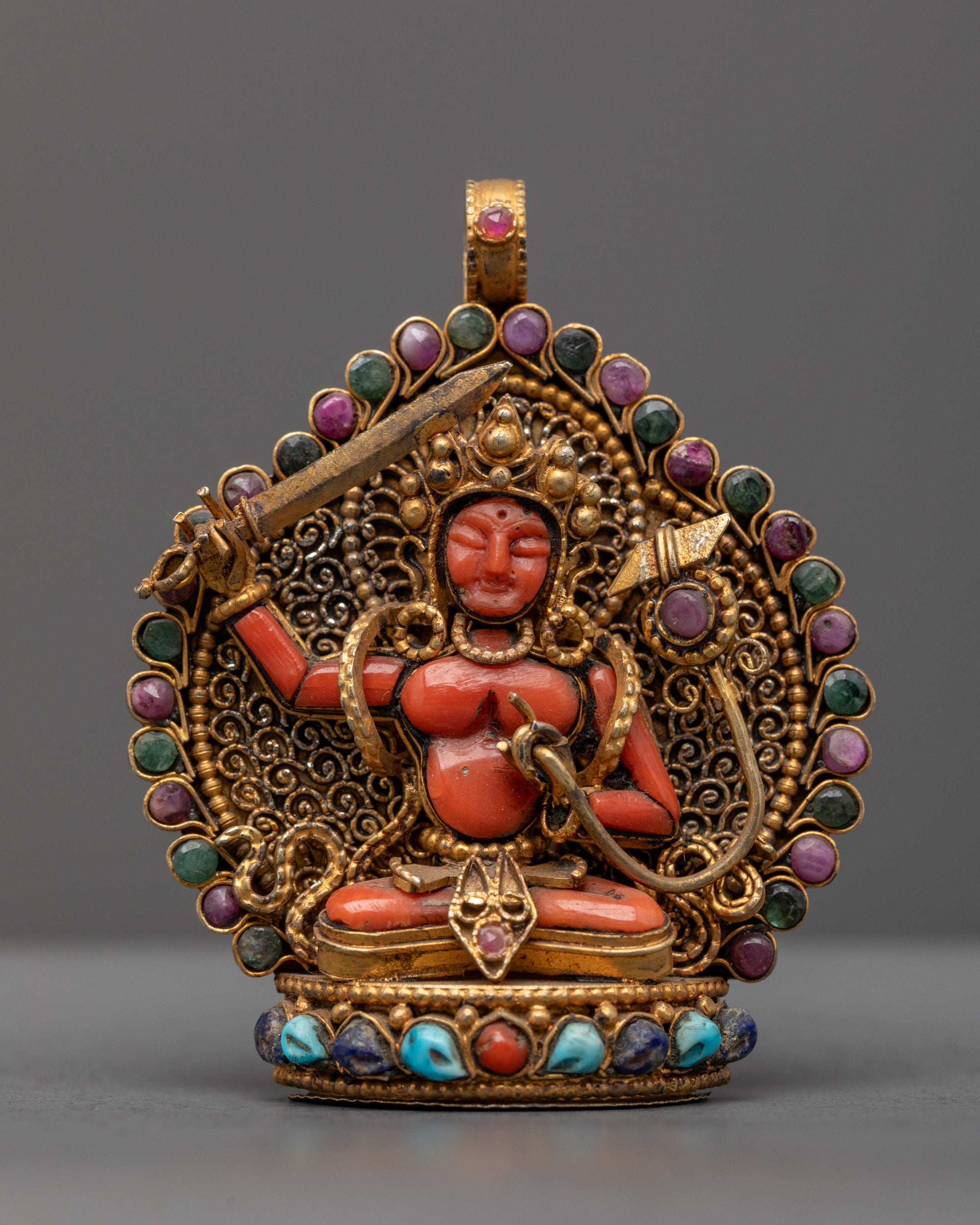 Front view of coral Manjushri locket with gold-gilded sword and intricate filigree design