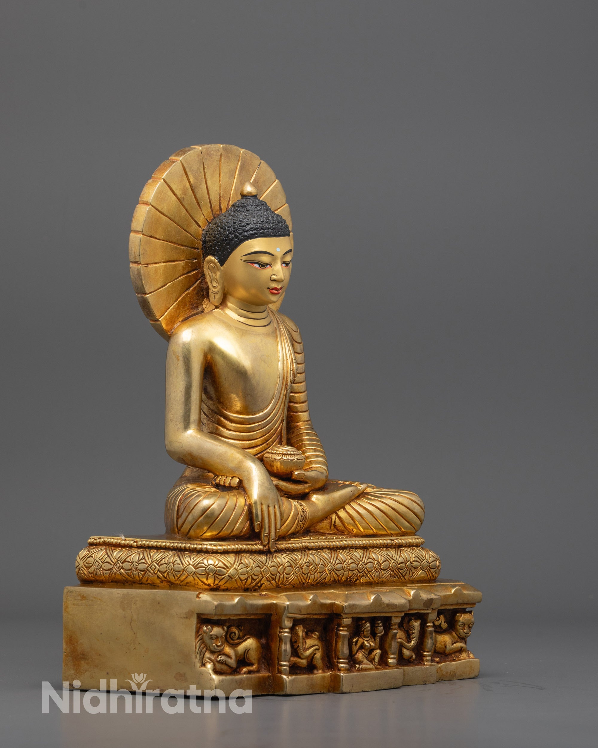Front view of gold-plated Siddhartha Gautama Buddha seated on a sacred plane base