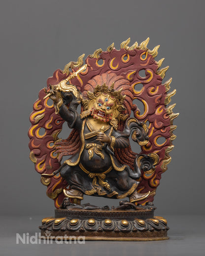 Front view of handcrafted Mahakala Statue with gold-gilded fierce face and crown crushing two humans
