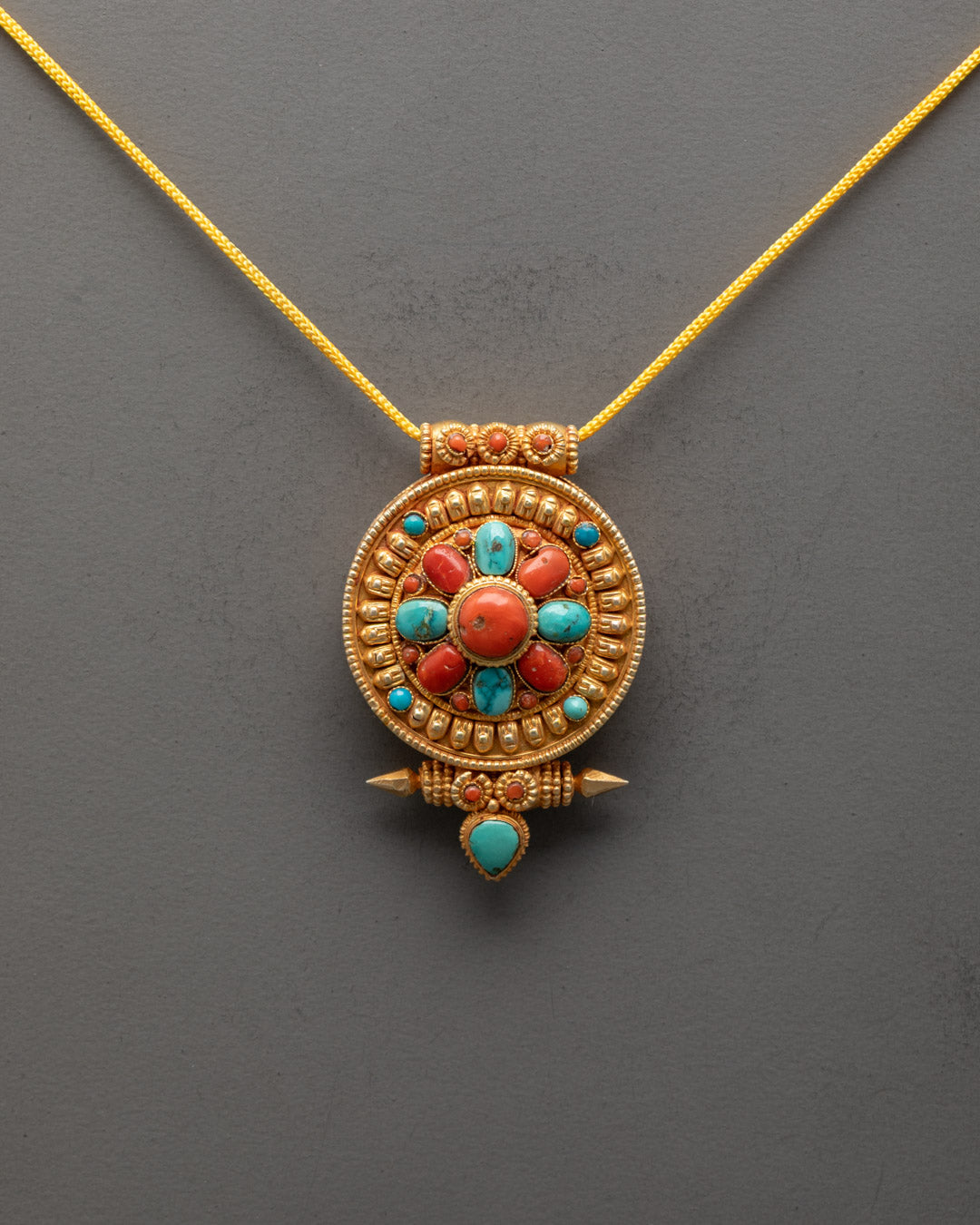 Front view of handcrafted Tibetan locket with turquoise and coral stones for protection

