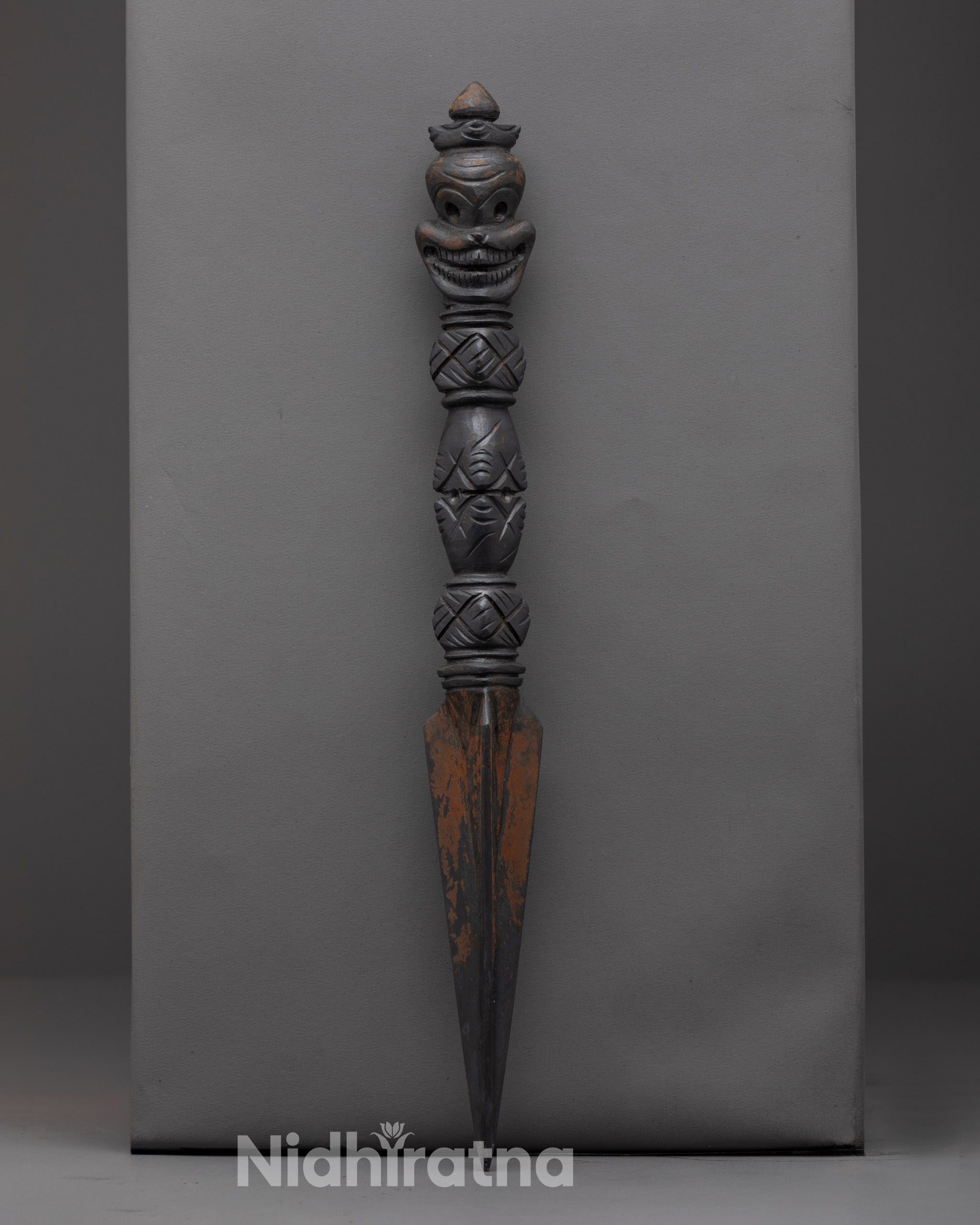 Front view of oxidized copper ritual dagger Phurba with intricate carvings
