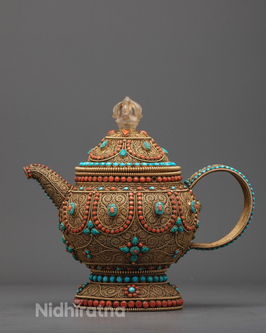 Front view of sacred Tibetan copper teapot with gold filigree and gemstones