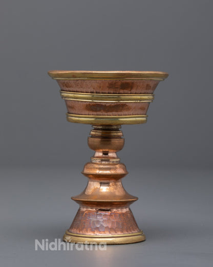 Front view of traditional copper Buddhist butter lamp on altar