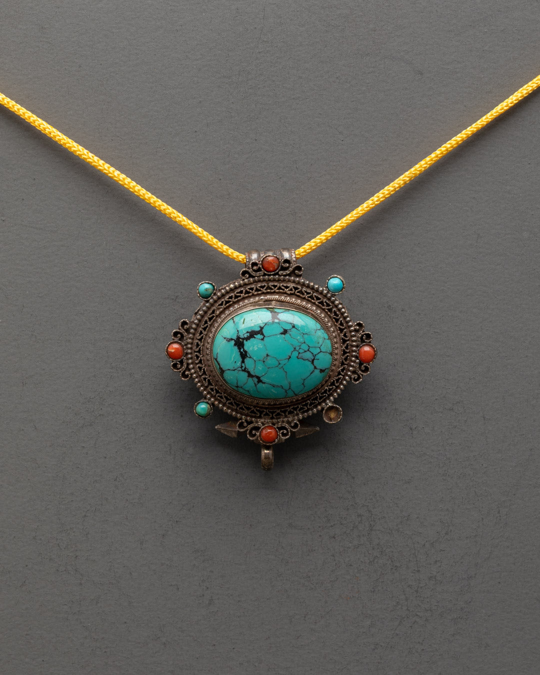 Front view of vintage Tibetan turquoise locket with copper filigree and gemstone inlay
