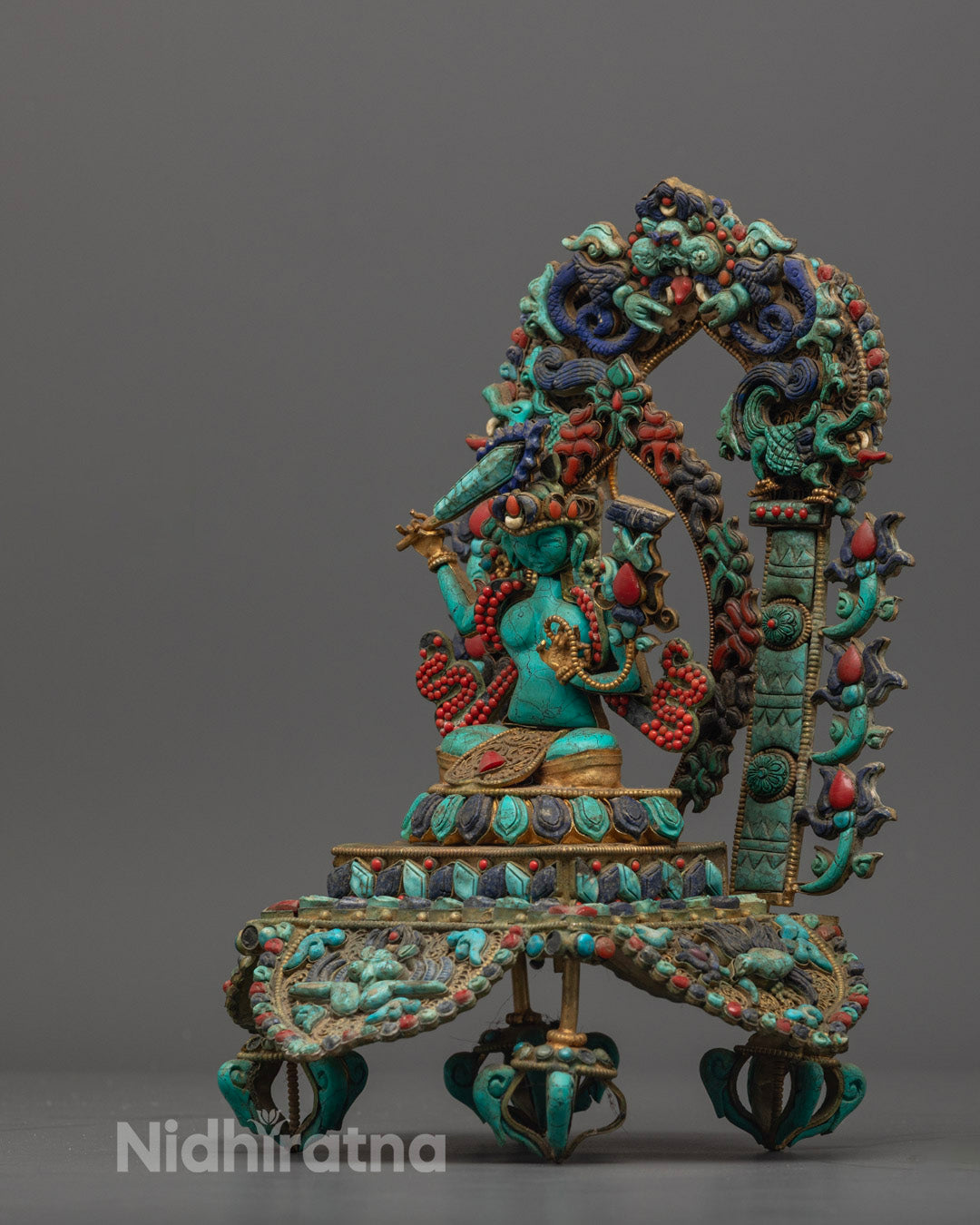 Manjushri statue seated on lotus base, decorated with semi-precious stones and vibrant colors.