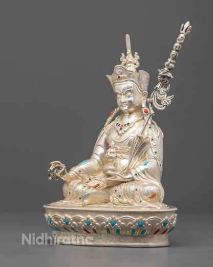 Nepalese Guru Rinpoche statue seated on lotus pedestal, featuring 24k silver plating and colorful semi-precious stone embellishments.