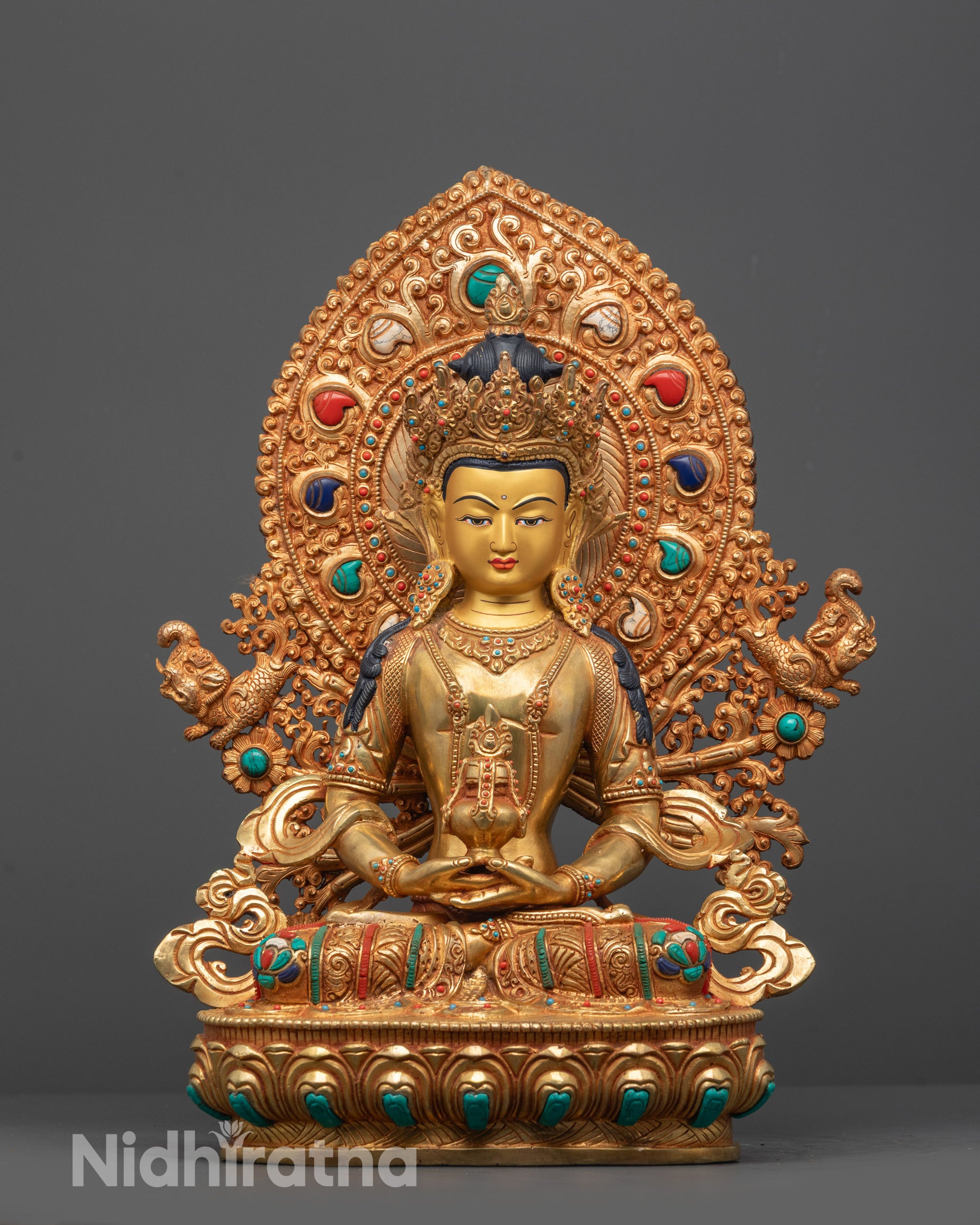 Gold-colored Amitayus statue with intricate designs and colorful gemstones on a gray background