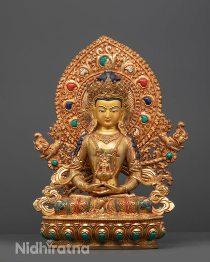 Gold-colored Amitayus statue with intricate designs and colorful gemstones on a gray background