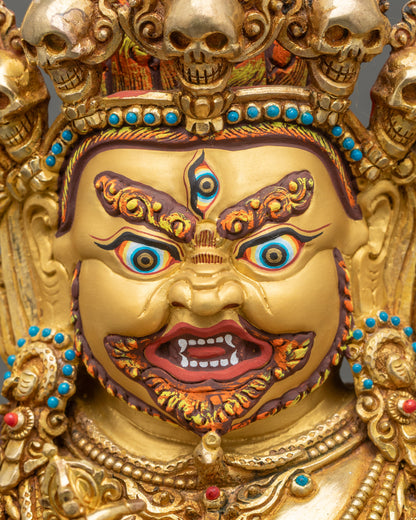 Gold-painted wrathful face of Mahakala with five-skull diadem, Tibetan protector deity.