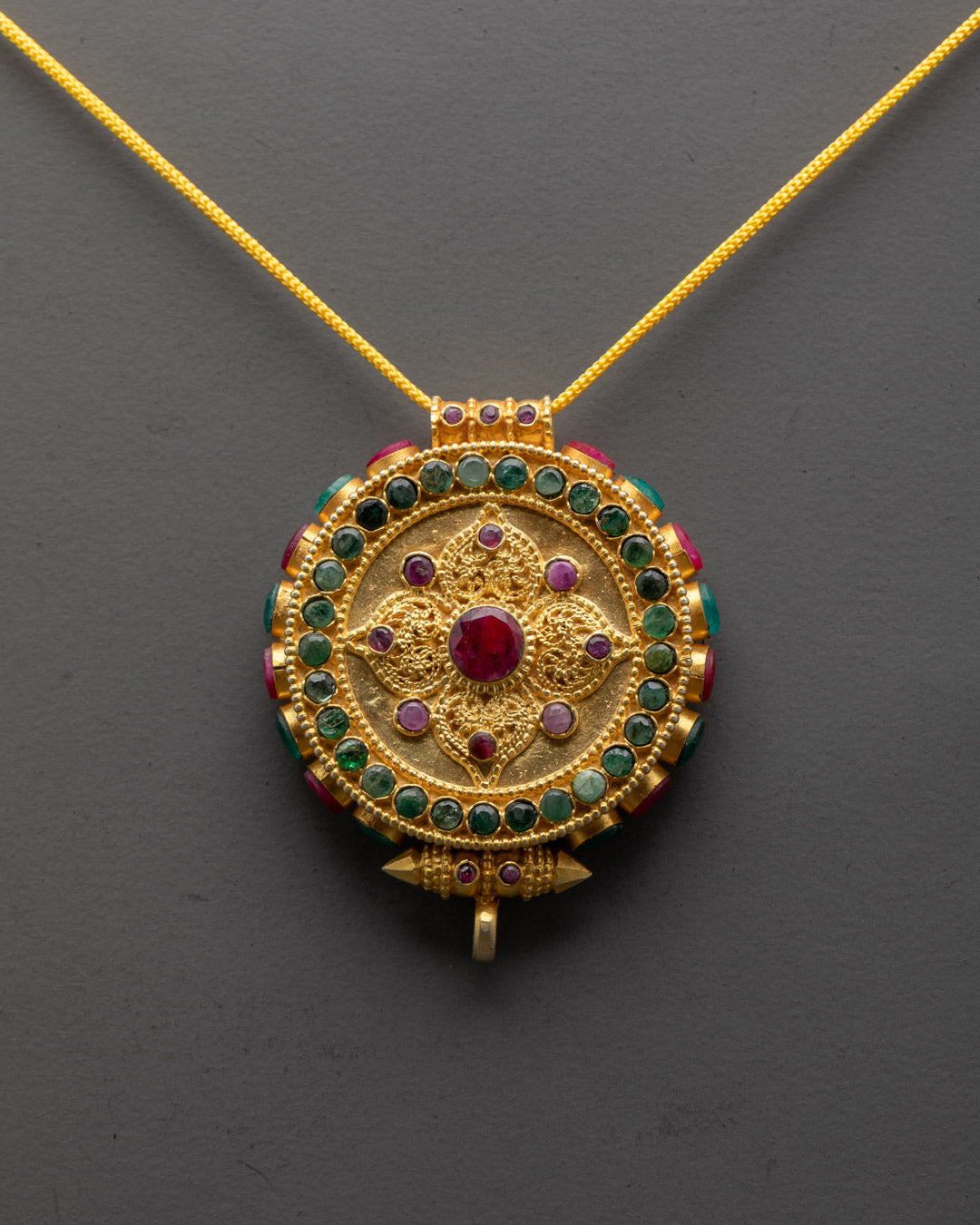 Gold Tibetan locket featuring detailed mandala carving and colorful coral accents