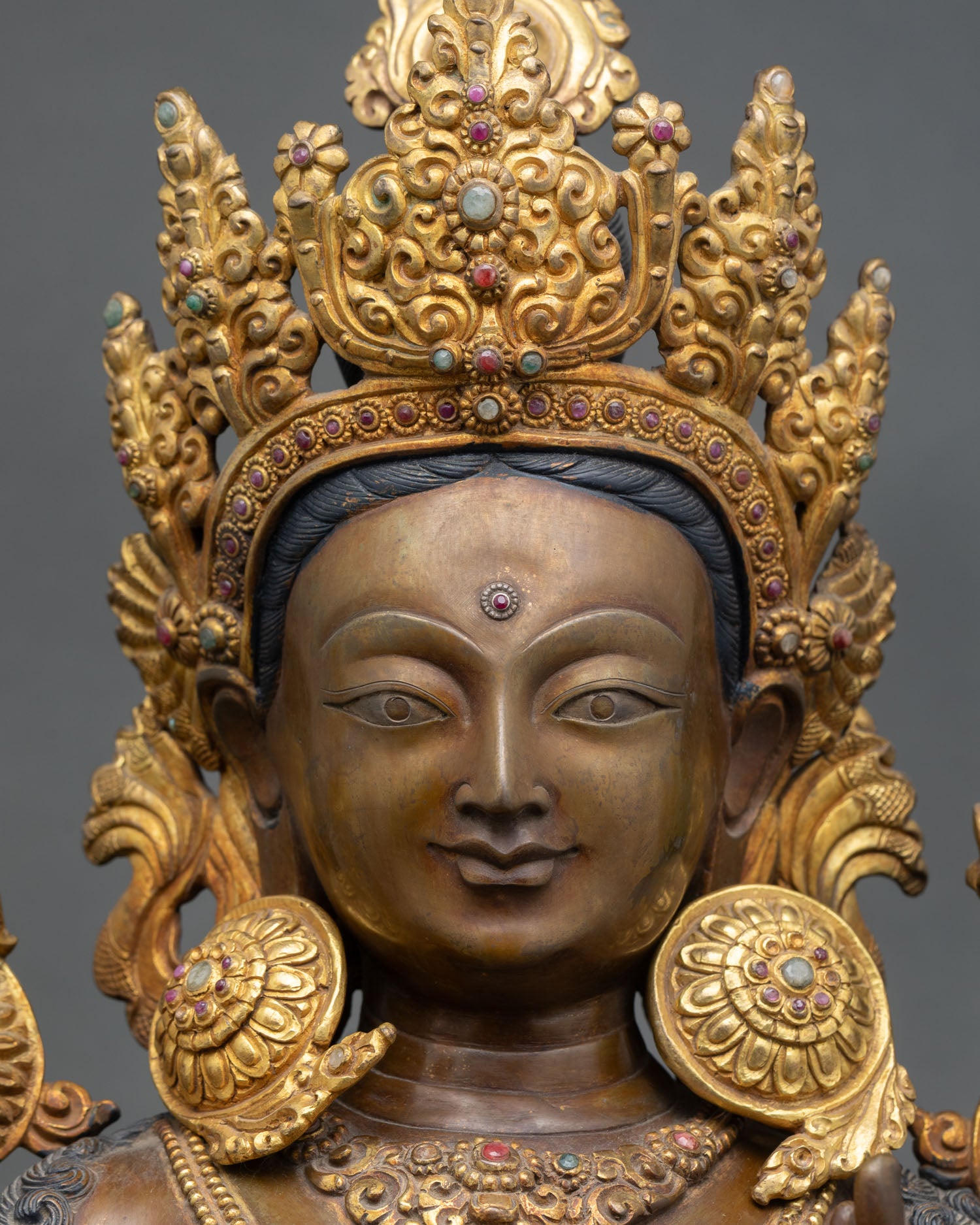 Green Tara face close-up, gold-painted serene expression, compassionate gaze