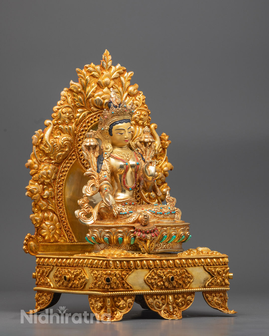 Side view showing varada mudra and utpala flower on gold-gilded Green Tara sculpture