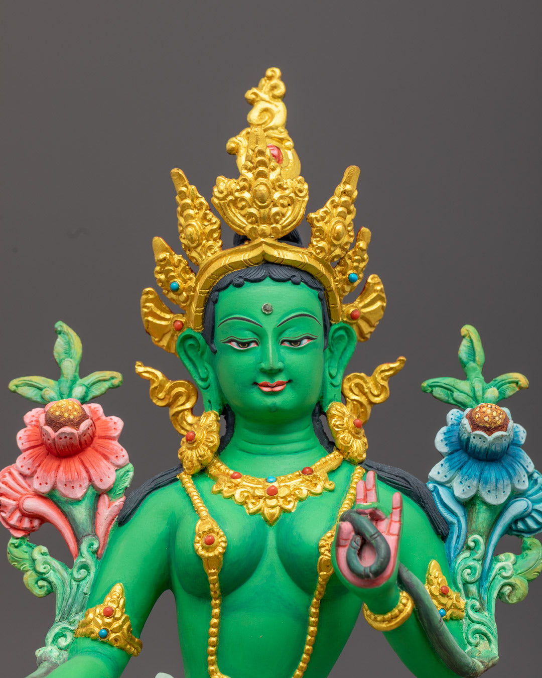 Serene face of Green Tara Buddha with delicate features, showing Varada mudra (blessing gesture) and holding a lotus stem