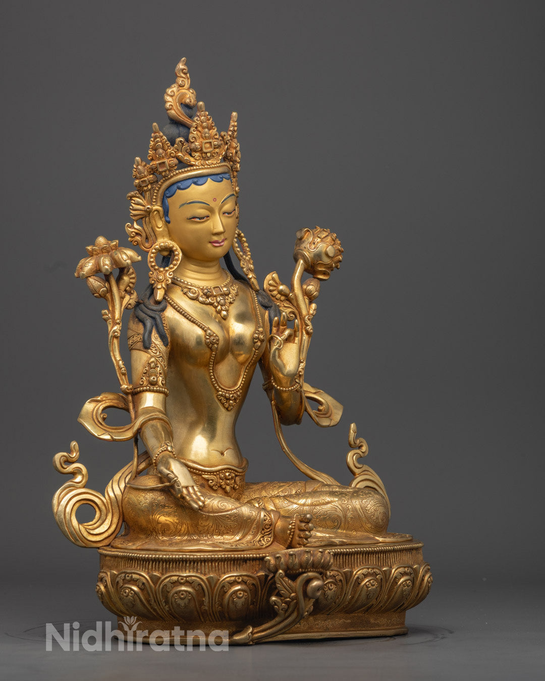 Green Tara Buddhist goddess statue adorned with jewelry, crown, and flowing robes, seated on lotus throne