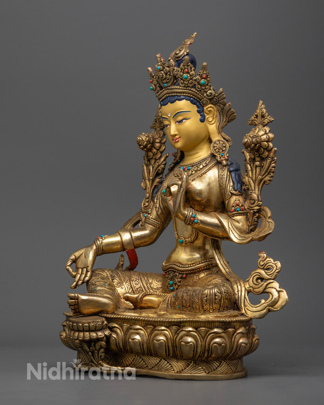 Green Tara Statue holding a blue lotus, symbolizing purity and compassion, adorned with semi-precious stones.