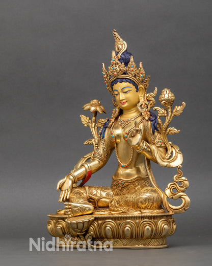 Green Tara deity statue left side showing folded left leg, raised left arm, and decorative details
