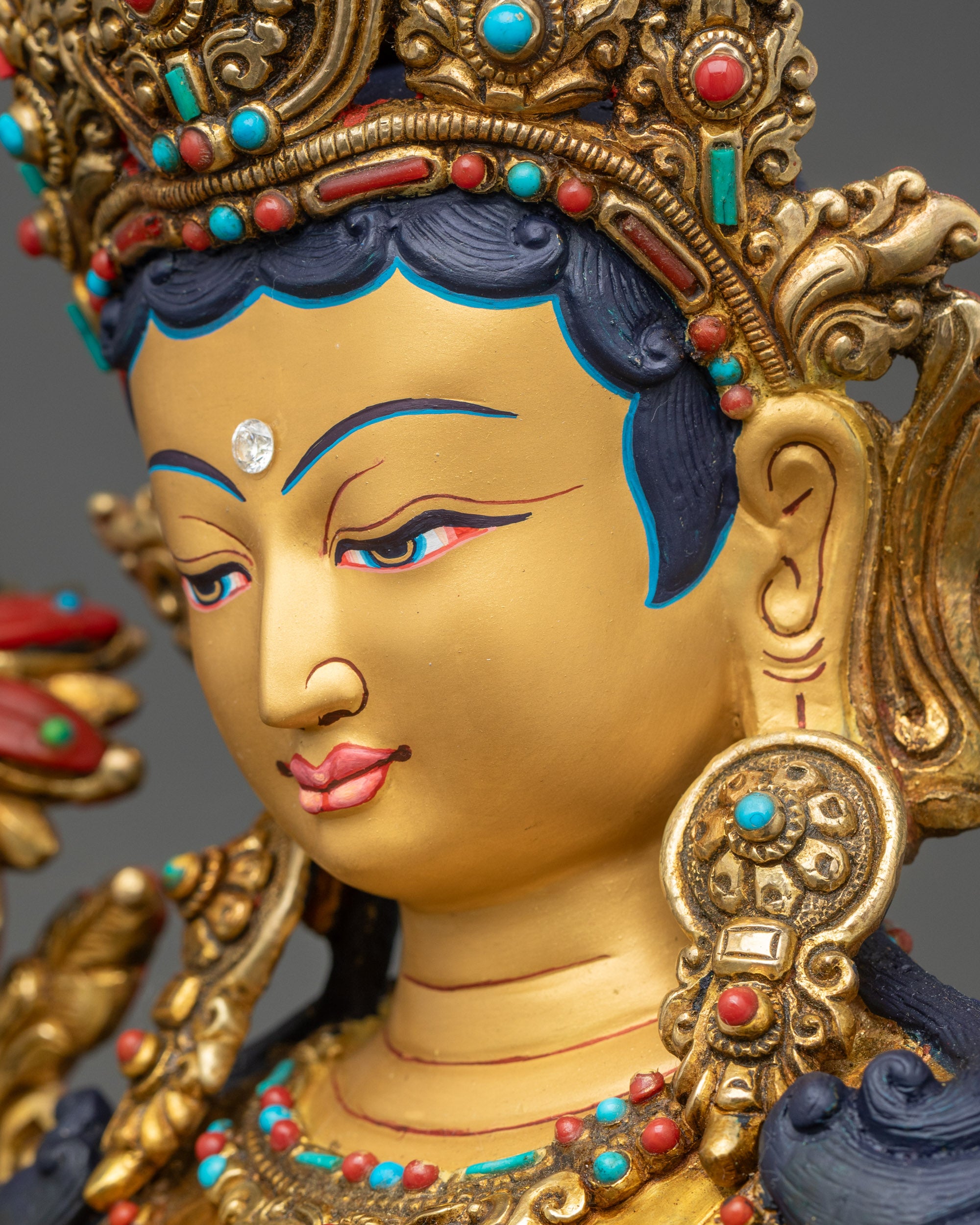 Green Tara statue detailed close-up of face, gold-gilded Bodhisattva expression