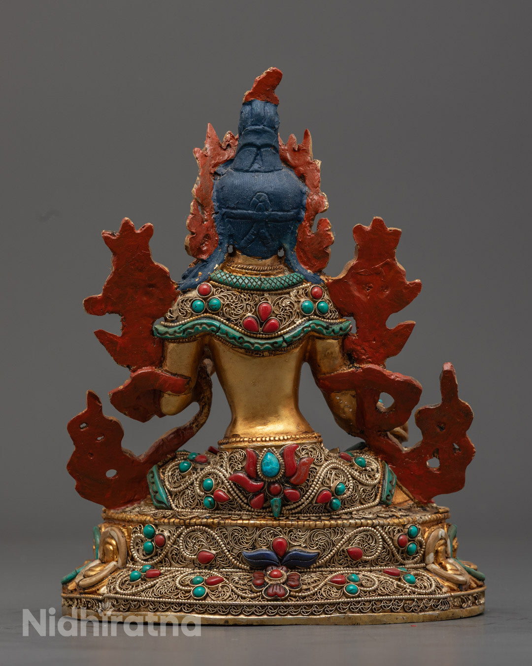 Green Tara statue holding a blue utpala flower, seated on a lotus throne adorned with semi-precious stones, symbolizing compassion and spiritual protection.