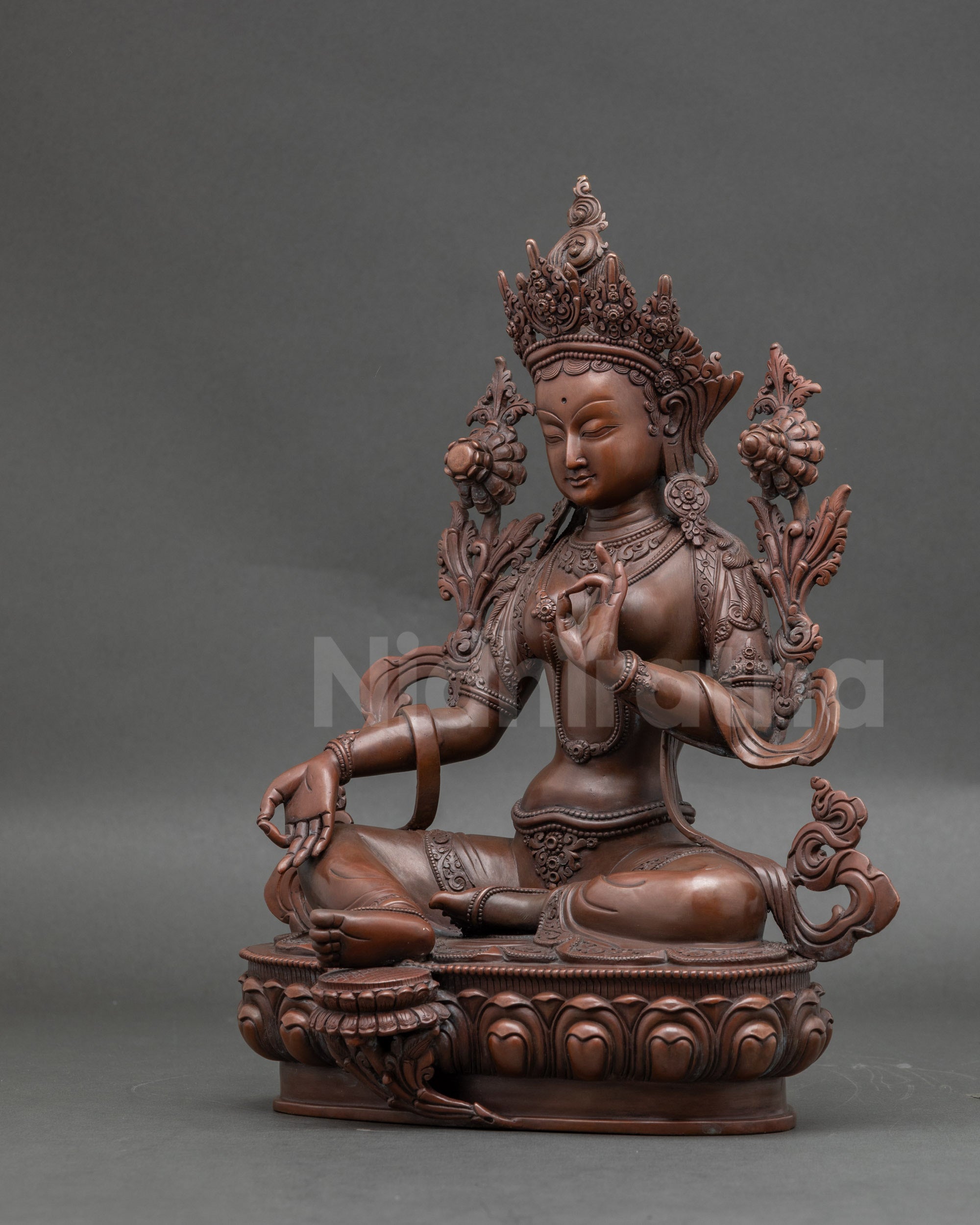 Green Tara statue in Lalitasana holding utpala flowers for healing and protection