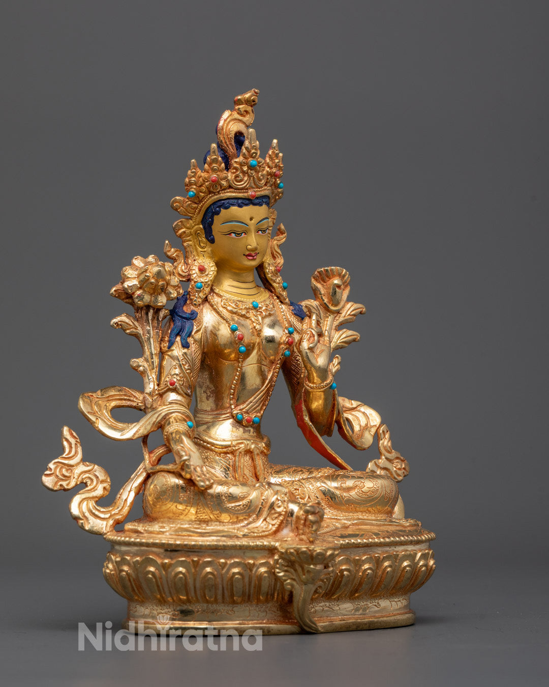 Side angle of Nepalese Green Tara statue holding utpala flowers